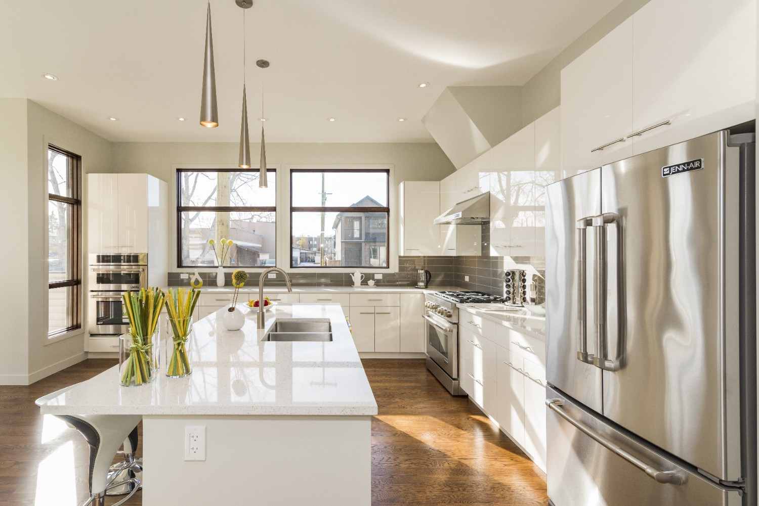 Bright modern white kitchen with a quartz island and stainless steel appliances