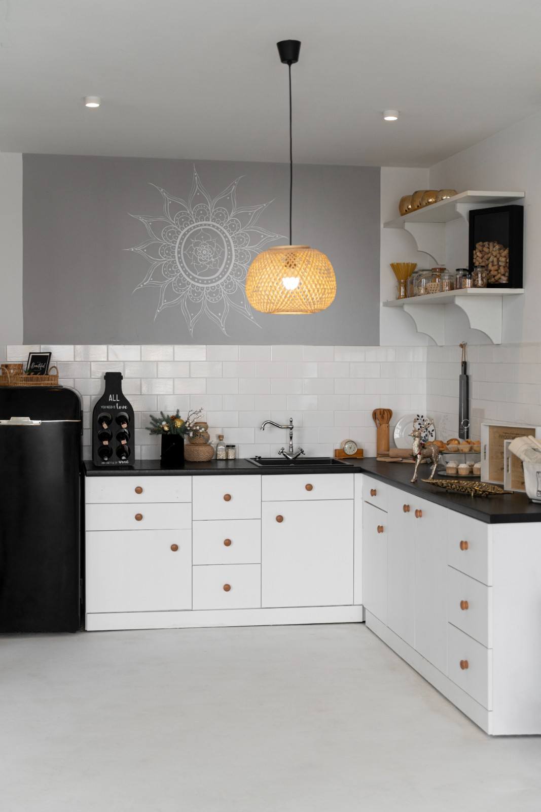 White kitchen cabinets with round wooden knobs and a black countertop