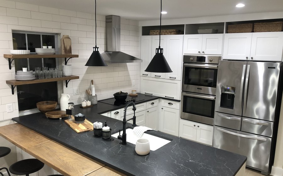White shaker kitchen cabinets with open shelving, a black countertop and stainless steel appliances