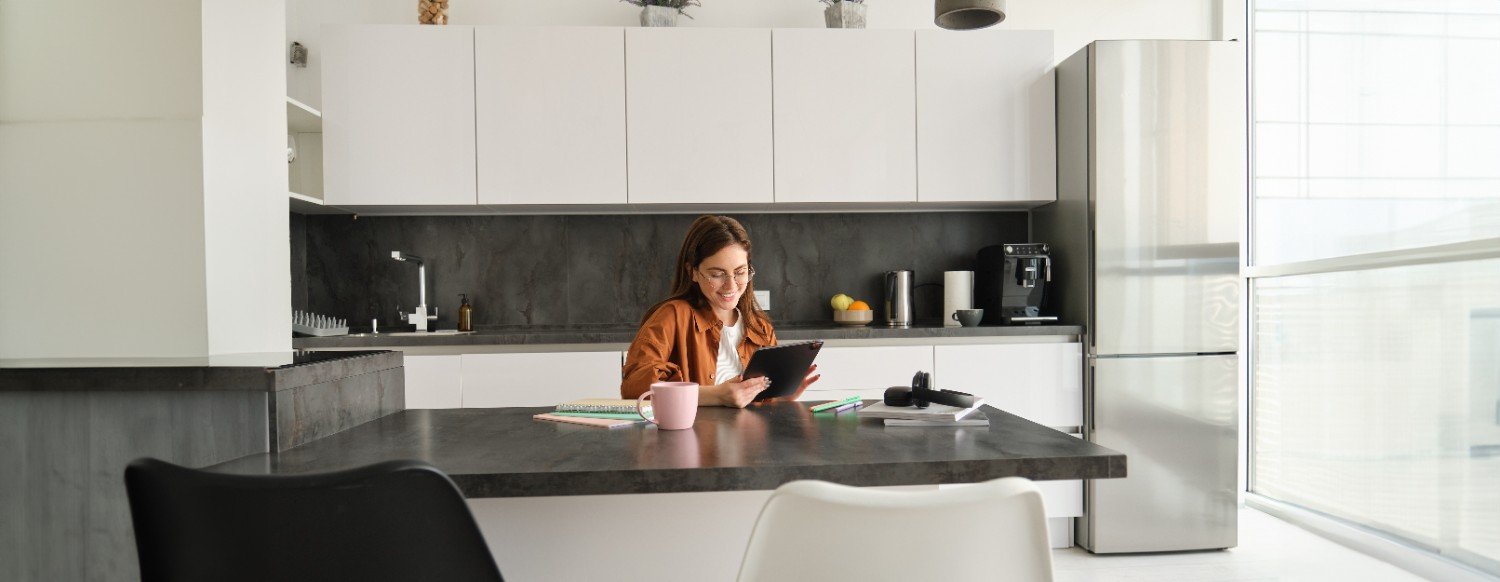 Woman using a tablet at a modern kitchen island with a dark stone countertop