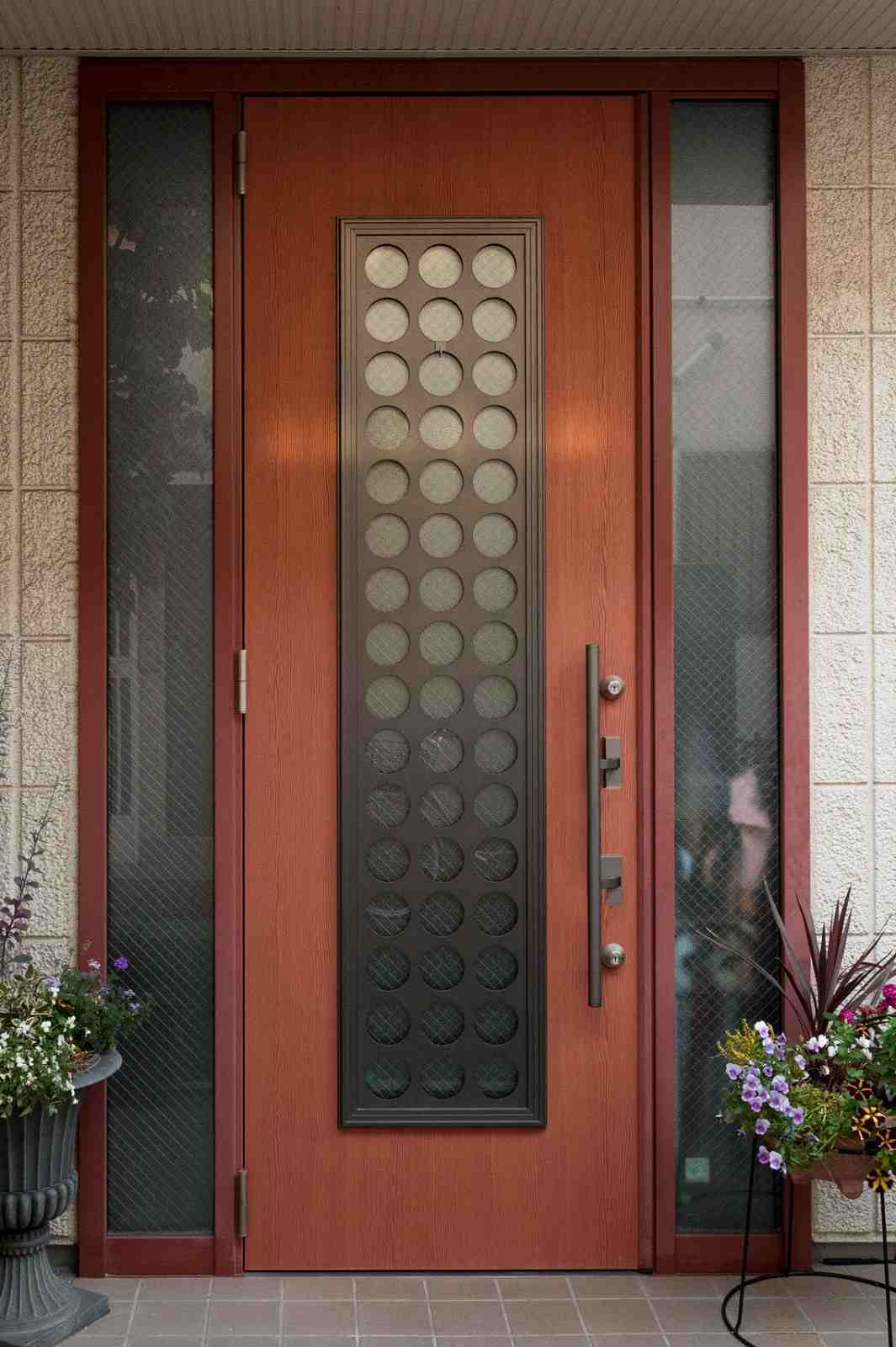 Wooden front door with circular glass panel and flower pots