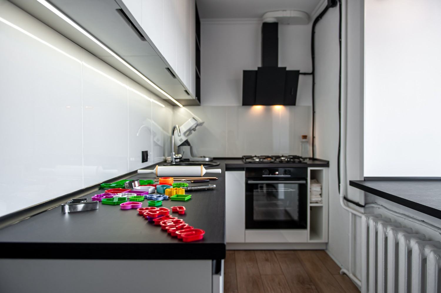 Sleek black and white kitchen with colourful cookie cutters on the counter