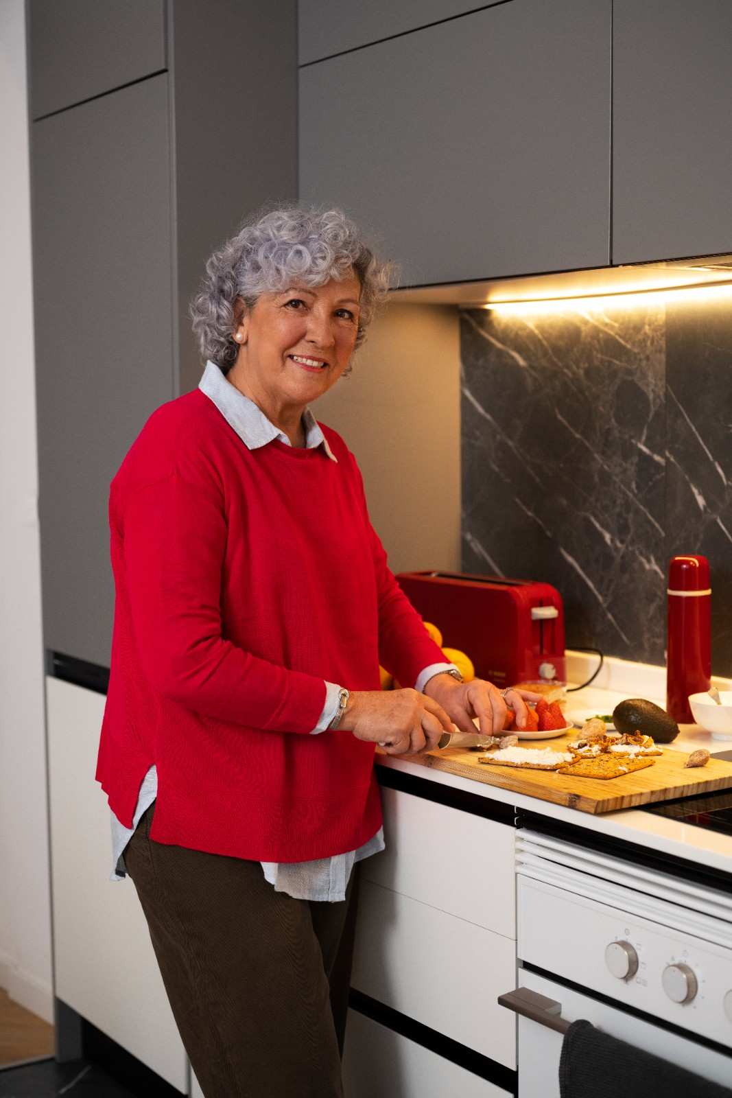 Smiling senior woman preparing a snack in a modern kitchen